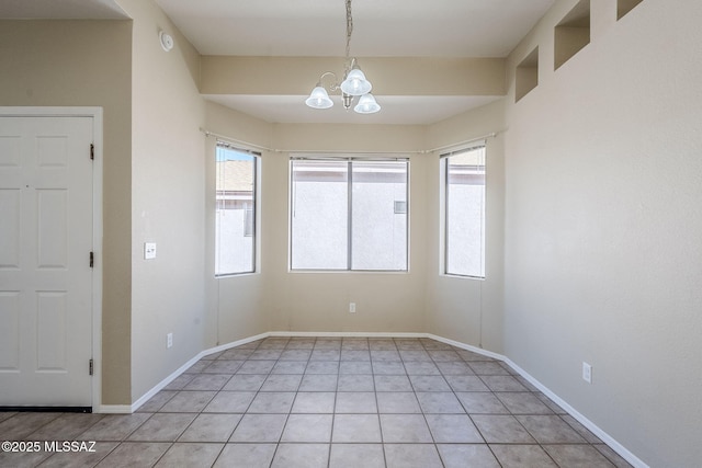 tiled spare room with plenty of natural light and a chandelier