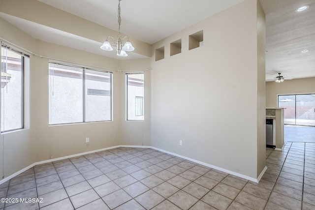 tiled spare room with ceiling fan with notable chandelier