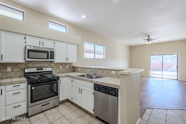 kitchen featuring sink, tile counters, white cabinets, and appliances with stainless steel finishes