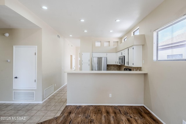 kitchen featuring light tile patterned floors, white cabinetry, backsplash, stainless steel appliances, and kitchen peninsula