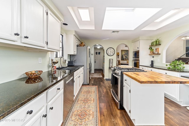 kitchen with a kitchen island, white cabinetry, sink, butcher block counters, and stainless steel appliances