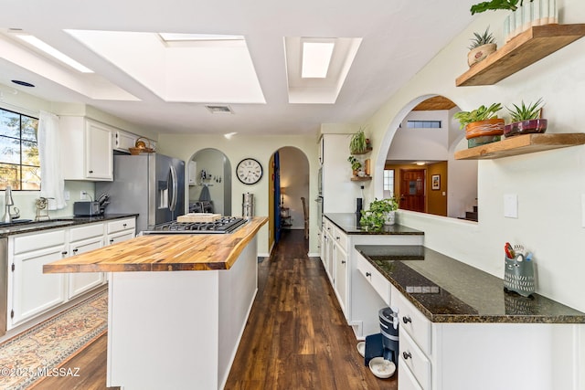 kitchen with stainless steel appliances, white cabinetry, butcher block counters, and sink