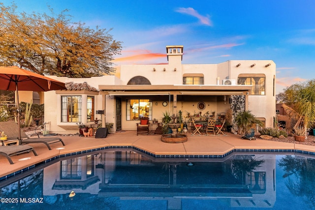 pool at dusk with a patio