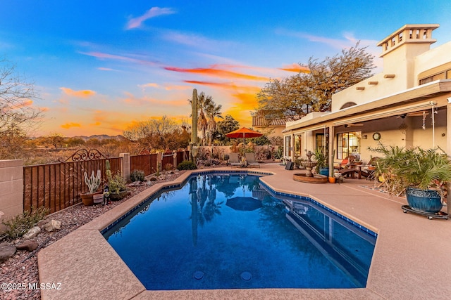 pool at dusk with a patio area