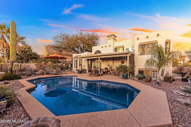 pool at dusk featuring a patio