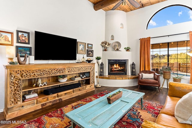 living room featuring a tile fireplace, hardwood / wood-style floors, high vaulted ceiling, beamed ceiling, and wooden ceiling