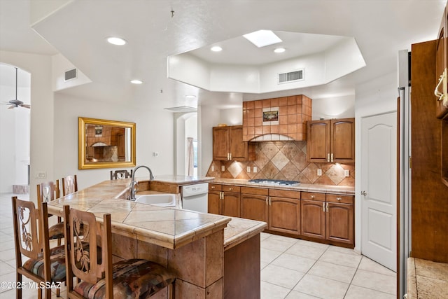 kitchen with sink, dishwasher, ceiling fan, tile counters, and decorative backsplash