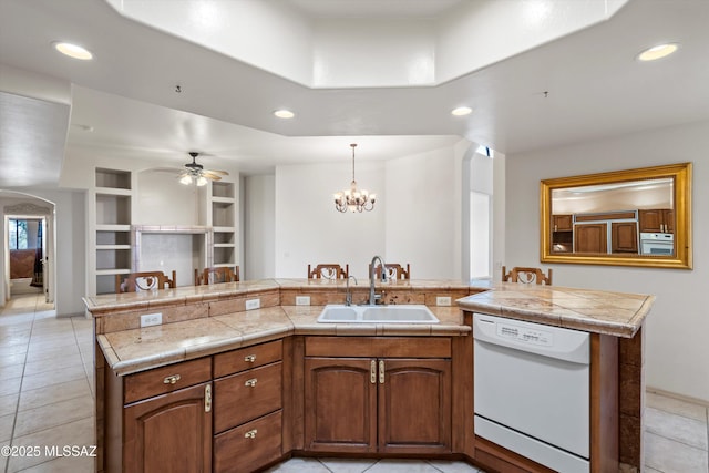 kitchen with built in features, sink, hanging light fixtures, a kitchen island with sink, and white appliances