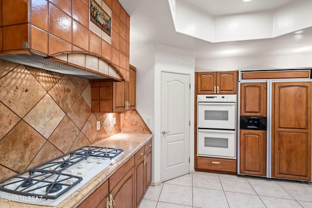 kitchen featuring white appliances, light tile patterned floors, and backsplash