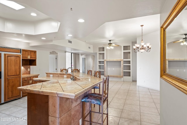 kitchen featuring decorative light fixtures, a breakfast bar area, paneled built in refrigerator, light tile patterned floors, and a spacious island