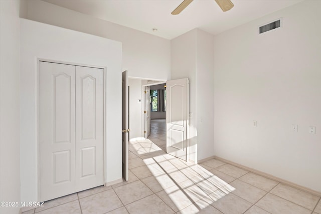 unfurnished bedroom featuring ceiling fan, a closet, and light tile patterned floors