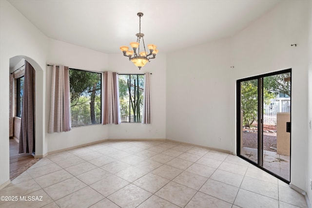 tiled empty room featuring a chandelier