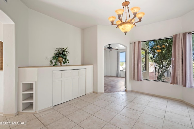 unfurnished dining area featuring light tile patterned floors and ceiling fan with notable chandelier