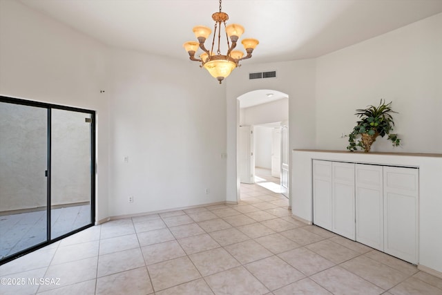 tiled spare room with a notable chandelier