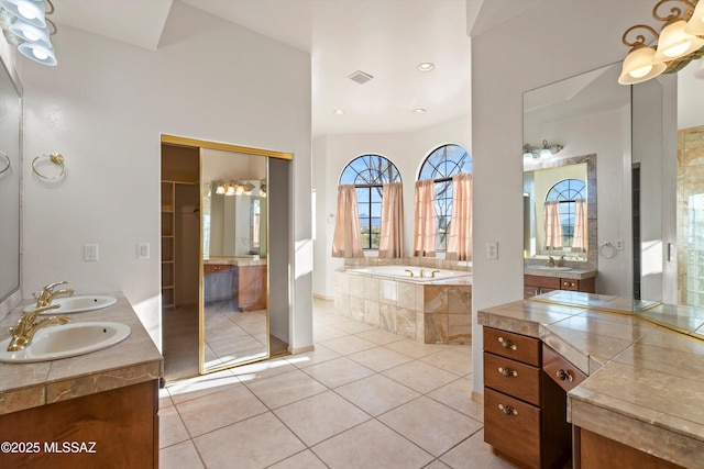 bathroom featuring tile patterned flooring, vanity, and tiled bath