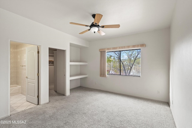 unfurnished bedroom featuring ensuite bath, light colored carpet, a closet, and ceiling fan