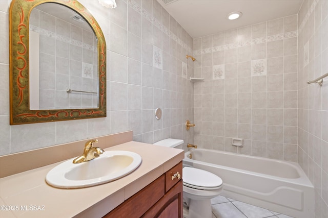 full bathroom with tile patterned floors, toilet, tiled shower / bath, tile walls, and vanity