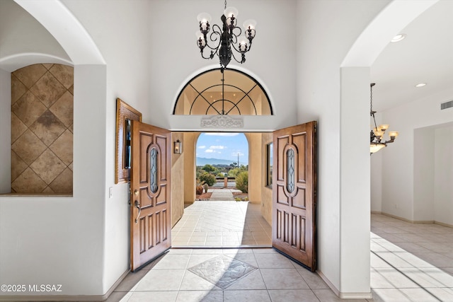 tiled foyer with an inviting chandelier and a towering ceiling