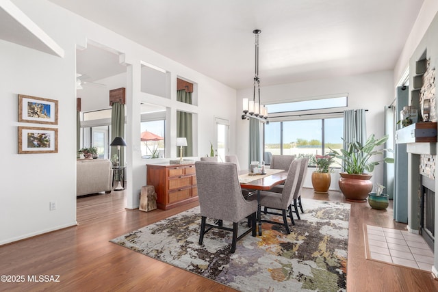 dining space with a fireplace with flush hearth, an inviting chandelier, and wood finished floors