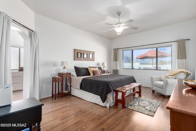 bedroom featuring a ceiling fan, arched walkways, and wood finished floors