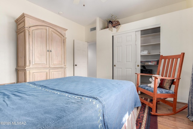 bedroom featuring a ceiling fan, visible vents, and wood finished floors