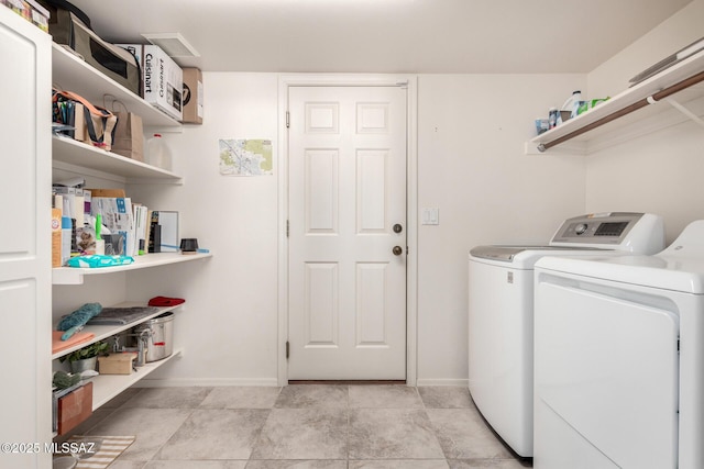 clothes washing area featuring laundry area, baseboards, and washer and clothes dryer