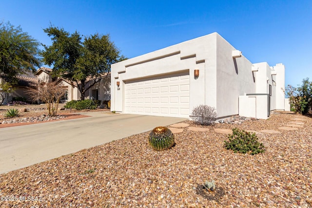 view of front of home with a garage, concrete driveway, and stucco siding