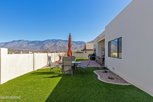 view of yard featuring a fenced backyard, a mountain view, and a patio