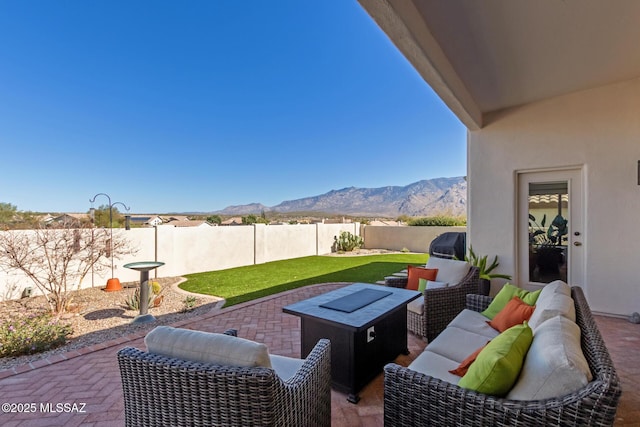 view of patio with an outdoor living space with a fire pit, a fenced backyard, and a mountain view