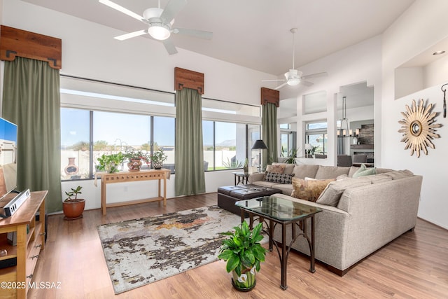 living area featuring ceiling fan, high vaulted ceiling, and light wood-style flooring