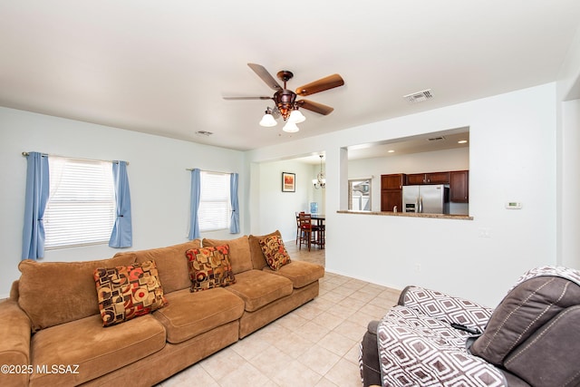 living room with ceiling fan with notable chandelier and light tile patterned floors