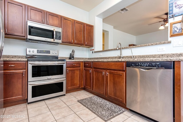 kitchen with light tile patterned floors, stainless steel appliances, and light stone countertops