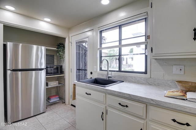 328 S Paseo Pena Unit C, Green Valley, AZ 85614 - kitchen featuring light countertops, white cabinets, a sink, light tile patterned floors, and freestanding refrigerator