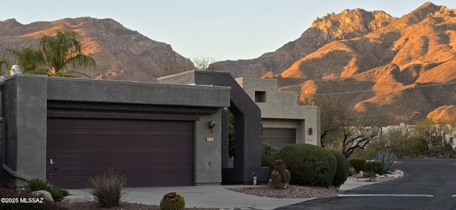 view of front facade featuring a mountain view, driveway, and stucco siding