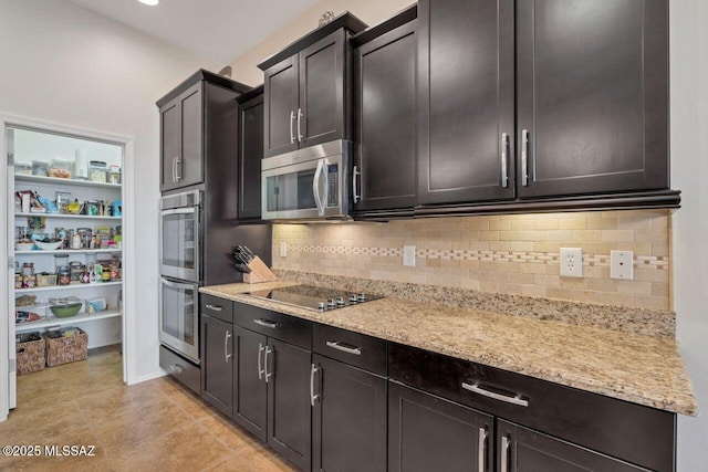 kitchen featuring light tile patterned flooring, appliances with stainless steel finishes, light stone countertops, and backsplash