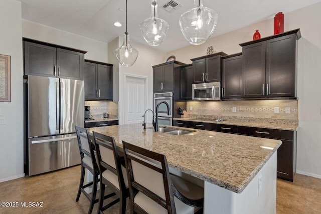 kitchen with visible vents, appliances with stainless steel finishes, a kitchen breakfast bar, and light stone counters