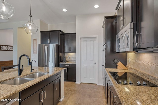 kitchen with a sink, tasteful backsplash, light stone countertops, appliances with stainless steel finishes, and hanging light fixtures