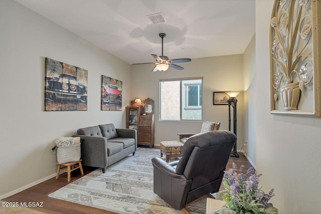 living room with baseboards, wood finished floors, visible vents, and ceiling fan