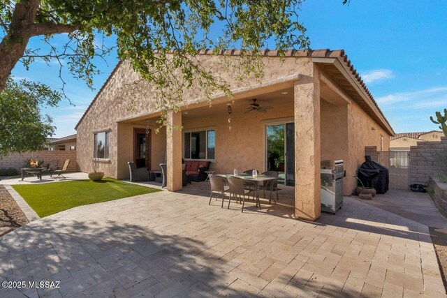 rear view of property featuring fence, a patio area, ceiling fan, outdoor dining space, and stucco siding