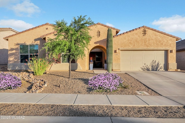 view of front of house featuring a garage, stucco siding, a tiled roof, and concrete driveway