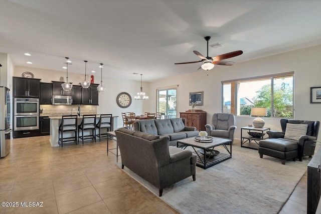 living room featuring ceiling fan with notable chandelier and light tile patterned floors