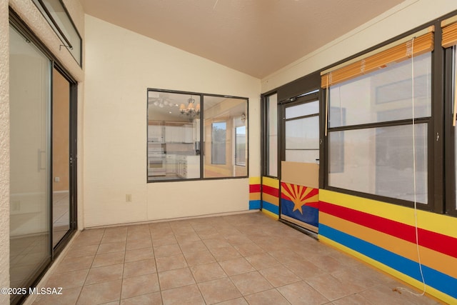 tiled empty room featuring vaulted ceiling