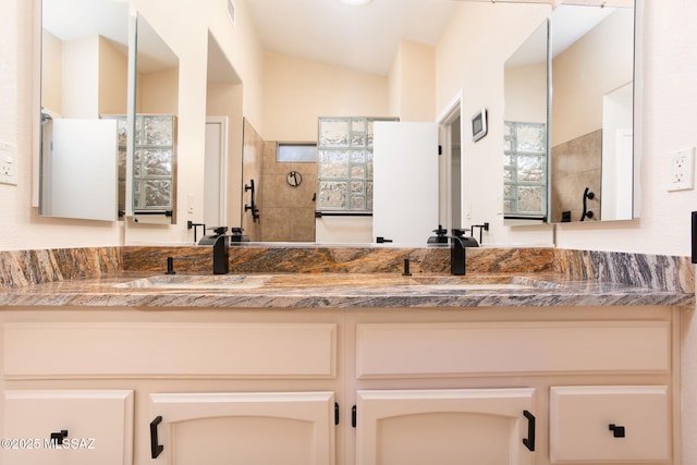 full bathroom featuring double vanity, visible vents, a sink, and lofted ceiling