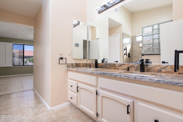 full bath featuring double vanity, plenty of natural light, a sink, and tile patterned flooring