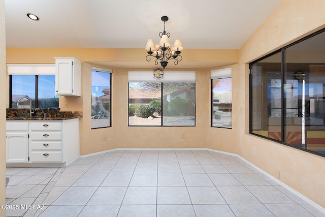 unfurnished dining area featuring a chandelier, light tile patterned floors, a sink, and baseboards