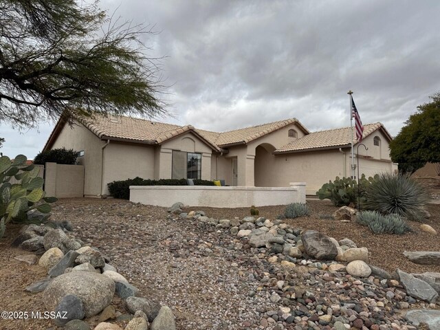 back of property with fence, a tiled roof, and stucco siding