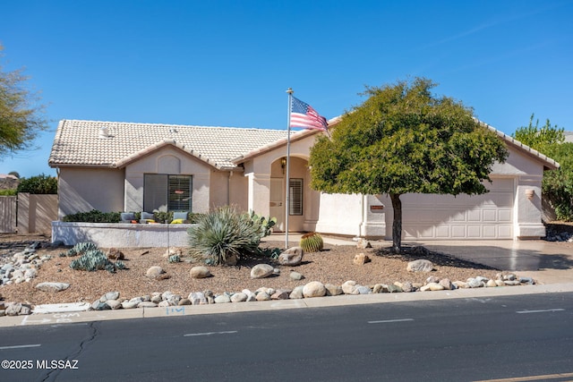 view of front of property with driveway, a garage, a tile roof, fence, and stucco siding