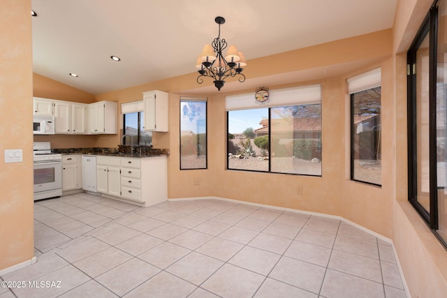 kitchen with lofted ceiling, white appliances, a sink, white cabinetry, and decorative light fixtures