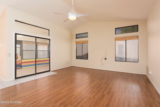 unfurnished room featuring light wood-style floors, a healthy amount of sunlight, and vaulted ceiling