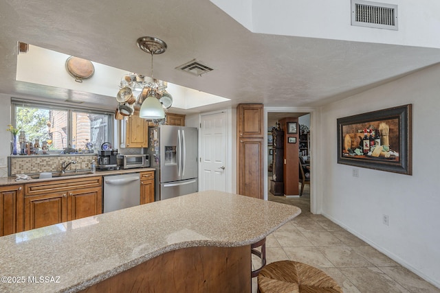 3910 S Via Del Ruisenor, Green Valley, AZ 85622 - kitchen with sink, appliances with stainless steel finishes, hanging light fixtures, a kitchen bar, and decorative backsplash